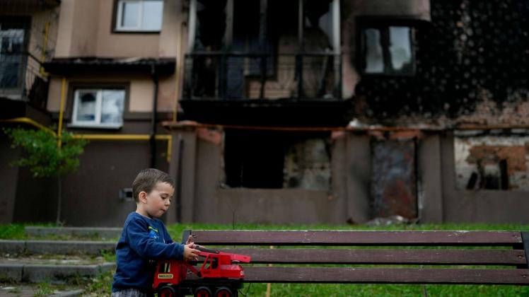 Vor einem zerstörten Gebäude in Irpin am Stadtrand von Kiew spielt der kleine Yarik mit seinem Spielzeug-Lastwagen. Foto: Natacha Pisarenko/AP/dpa