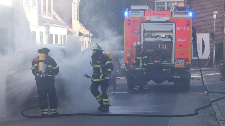 Einsatz am Montagabend: Feuerwehrleute löschen den brennenden Wagen in der Glückstädter Innenstadt.