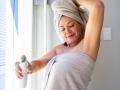 Smiling woman wearing towel spraying deodorant on body at home model released, Symbolfoto property released, ESTF00025