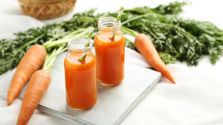 Fresh carrot juice in bottles on a white wooden table (5second)