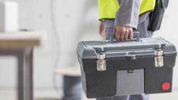 Close up of construction worker carrying tool box model released Symbolfoto property released PUBLIC