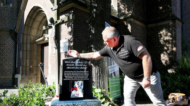 Missbrauchsopfer Markus Elstner enthüllet einen Gedenkstein vor der St. Cyriakus-Kirche in Bottrop. Foto: Roland Weihrauch/dpa