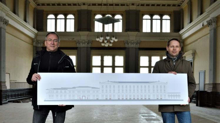 Torsten Diehn (l.) und Wittenberges Bauamtsleiter Martin Hahn präsentieren den Plan zum Bahnhofsumbau in der Empfangshalle. 