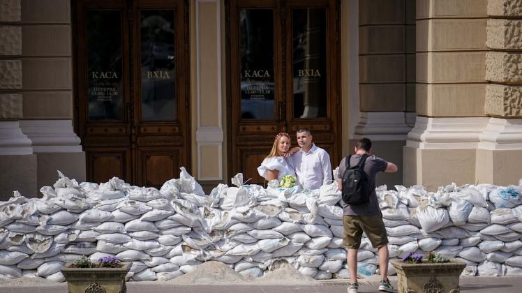 Alesya und Gena lassen sich kurz nach ihrer Trauung hinter einem Schutzwall aus Sandsäcken vor der Oper von Odessa fotografieren. Foto: Kay Nietfeld/dpa