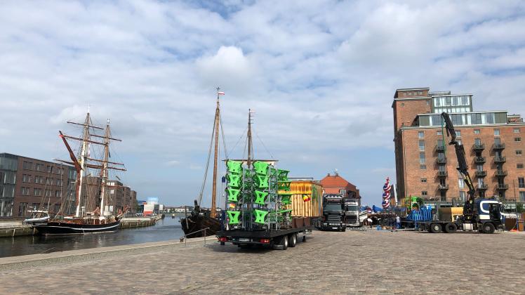Am Alten Hafen in Wismar haben die Vorbereitungen für das Hafenfest begonnen. Ein Schiff ist schon da und die Schausteller bauen ihre Stände auf.