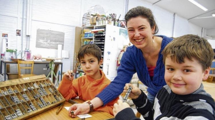 Die Teamarbeit klappt bei Darius (links) und Elias (rechts) perfekt. Cristina Müller ist begeistert, wie die Jungen sich die Arbeit beim Letternsetzen aufteilen. Fotos: Stefanie Hiekmann