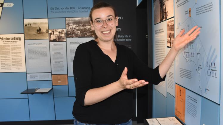 Luisa Taschner zeigt mit beiden Händen auf die Dauerausstellung im Grenzhus Schlagsdorf.