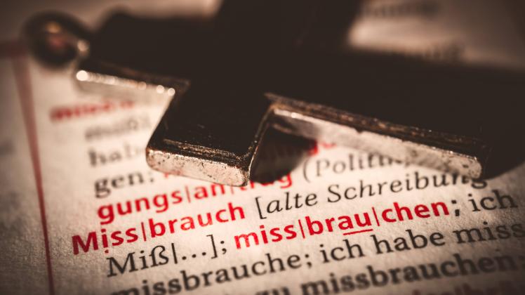 Kreuz auf einem Wörterbuch mit dem Wort Missbrauch Symbolfoto Missbrauchsskandal *** Cross on a dic