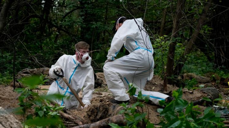 dpatopbilder - Zwei Ermittler in Schutzkleidung arbeiten während einer Exhumierung an einem Massengrab in der Nähe von Butscha unweit von Kiew. Nach ukrainischen Angaben kamen im russischen Angriffskrieg bislang mehr als 12.000 Zivilisten ums Leben. Foto: Natacha Pisarenko/AP/dpa