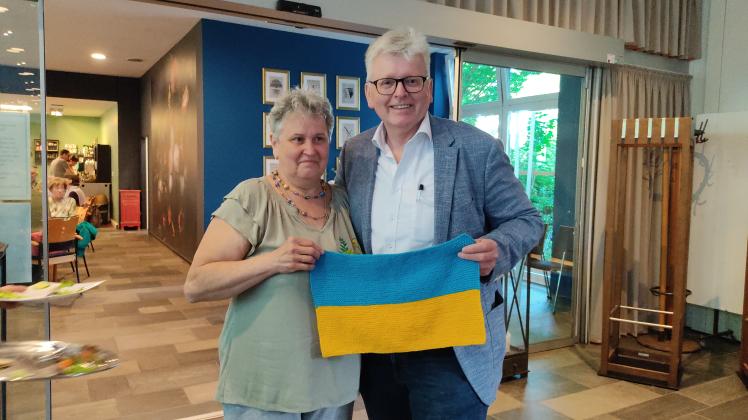 Neubürgerin Nadia Kolomiets aus Charkow im Nordosten der Ukraine übergibt Bürgermeister Klaus Rehkämper eine kleine selbstgestrickte ukrainische Flagge. 