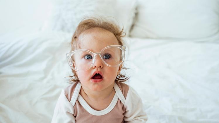 Cute girl wearing eyeglasses sitting on bed at home model released Symbolfoto property released VPIF04336