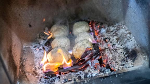 Auf einer Pappe kommen die Salzteig-Bällchen in die Glut. Foto: Florian Schuh/dpa-tmn Auf einer Pappe kommen die Salzteig-Bällchen in die Glut. Foto: Florian Schuh/dpa-tmn