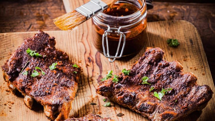 Three portions of spicy grilled ribs basted with a savory aromatic sauce and garnished with herbs fo