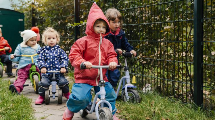 Children using scooters in garden of a kindergarten model released Symbolfoto property released PUBL