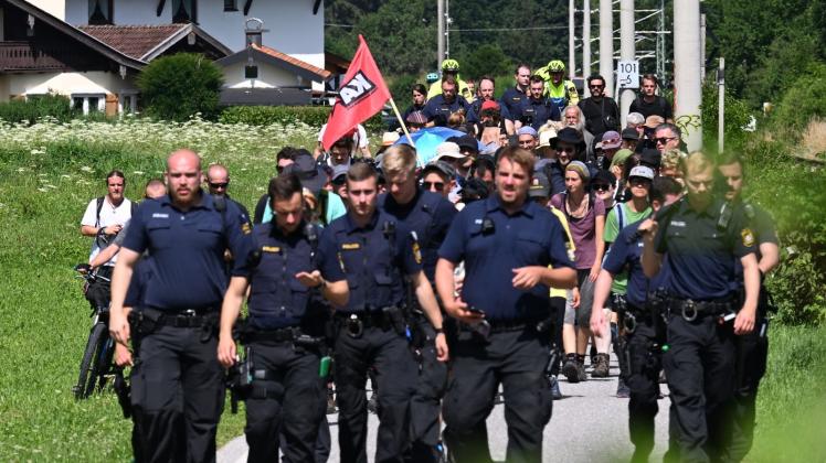 Aktivisten auf einem Sternmarsch zum G7-Gipfel werden von Polizisten begleitet. Foto: Angelika Warmuth/dpa