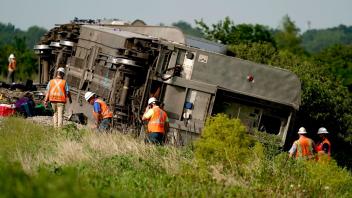 Arbeiter inspizieren die Stelle, an der der Zug entgleiste. Foto: Charlie Riedel/AP/dpa
