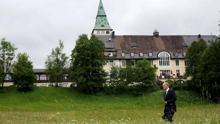 Germany&apos;s Chancellor Olaf Scholz walks through the grass as he arrives to give a statement on June 28, 2022 at Elmau Castle, southern Germany, at the end of the G7 Summit. (Photo by Ronny HARTMANN / AFP)