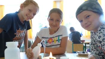 (Carolin ( von links), Dana und Leonie produzieren aus einfachen Zutaten Löschschaum, der die Flamme erstickt.
