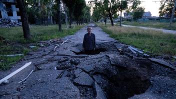 Viktor Schewtschenko steht in einem Krater, der bei einem russischen Angriff auf den Stadtteil Saltiwka in Charkiw entstanden ist. Foto: Evgeniy Maloletka/AP/dpa