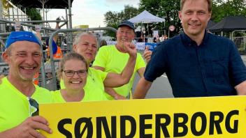 Vier Männer halten ein Schild mit der Aufschrift „Sonderburg“.