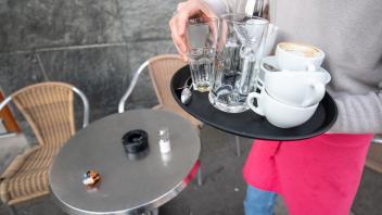 ARCHIV - Eine Servicekraft räumt die Tische in einem Café ab. Foto: Sebastian Gollnow/dpa/Symbolbild