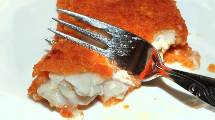 Fisch als Lebensmittel Alaska Seelachsfilet liegt fertig zubereitet auf einem weißen Teller und wird