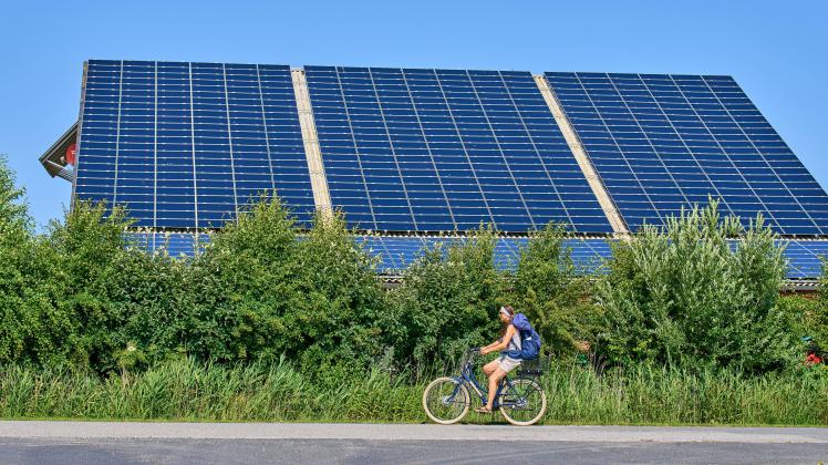 Woman on a cycle passing photovoltaik panels on June 29, 2022 in Wyk, Foehr Island, Germany.