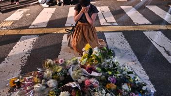 A woman reacts in front of a makeshift memorial where people place flowers at the scene outside Yamato-Saidaiji Station in Nara where former Japanese prime minister Shinzo Abe was shot earlier in the day on July 8, 2022. - Abe was pronounced dead on July 8, the hospital treating him confirmed, after he was shot at a campaign event in the city of Nara. (Photo by Philip FONG / AFP)