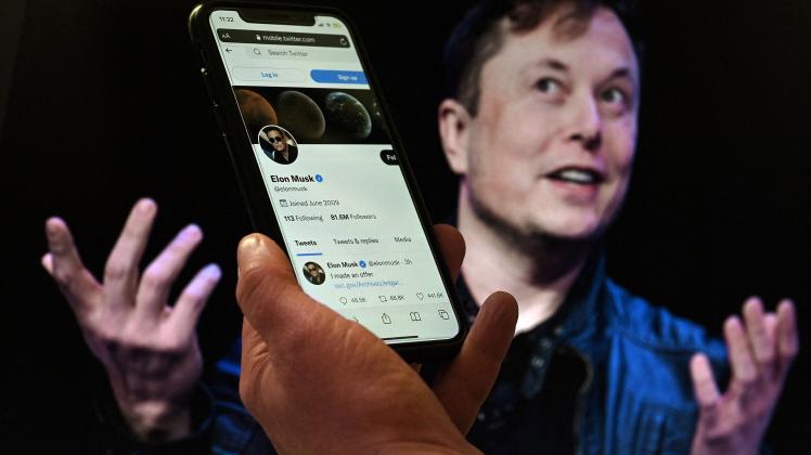 (FILES) In this file photo illustration, a phone screen displays the Twitter account of Elon Musk with a photo of him shown in the background, on April 14, 2022, in Washington, DC. - Elon Musk pulled the plug on his deal to buy Twitter on July 8, 2022, accusing the company of "misleading" statements about the number of fake accounts, a regulatory filing showed (Photo by Olivier DOULIERY / AFP)