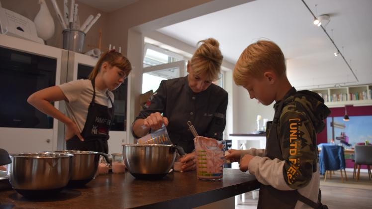 Bettina Seitz (Mitte) zeigt Anne Kathrin (11) und Hannes, wie man die Heidelbeer-Joghurt-Creme schön anrichtet.