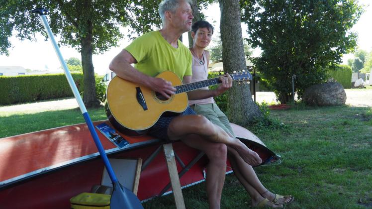 Mit der Gitarre sitzen Thomas und Mireille Davids auf ihrem Kanu und genießen die Ruhe auf dem Campingplatz in Eldena. 