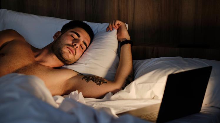 Young man sleeping by illuminated laptop in bed at home model released, Symbolfoto property released, AODF00602