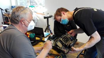Zwei ehrenamtliche Reparateure des Vereins kümmern sich um ein Elektrogerät.  