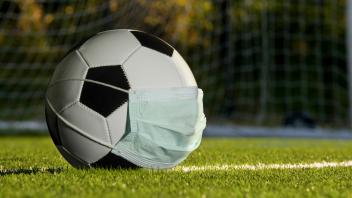 soccer ball wearing a mask, concept of sports suffering from the COVID-19 pandemic.