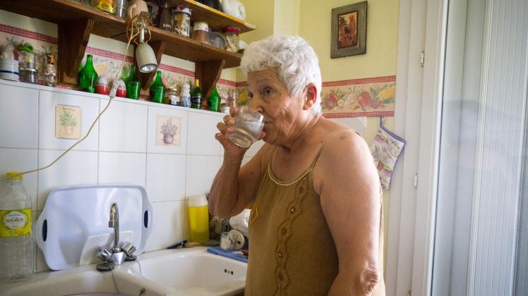 Jackye Lafon, an 81-year-old retiree, drinks water in her flat of the Cite Bourbaki in the Minimes district of Toulouse on July 14, 2022. - France is witnessing a second heatwave in less than a month, "a sign of climate change and hotter summers to come where 35 degrees will be the norm" said the French weather broadcast company Meteo France. (Photo by FRED SCHEIBER / AFP)