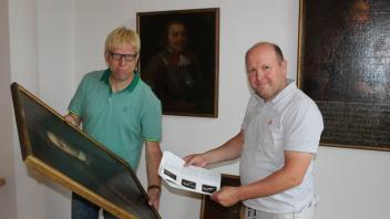 Wer ist dieser Ritter? Sebastian Hüdepohl (links) und Stefan Walter haben für das Anbringen der historischen Gemälde einen genauen Plan.