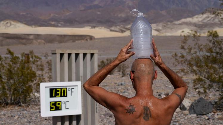 ARCHIV - Ein Mann kühlt sich im «Death Valley»-Nationalpark mit einer mit Eiswasser gefüllten Plastikflasche auf dem Kopf ab. Foto: John Locher/AP/dpa
