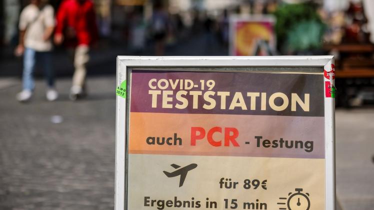 Ein Schild weist in der Innenstadt von Halle auf eine PCR-Teststation hin. Foto: Jan Woitas/dpa
