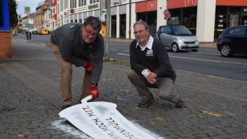 Holger Fockenga (von links) und Ingo Kühl vom TBZ sprühen das Motiv auf die Gehwege in der Innenstadt.