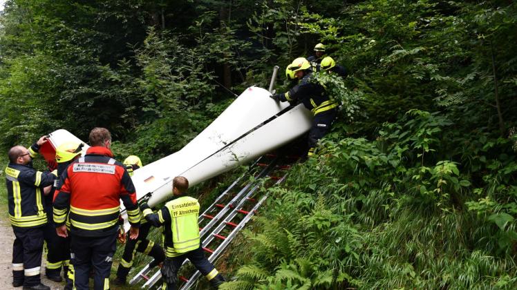 Feuerwehrleute bergen das Wrack des  abgestürzten Ultraleichtflugzeugs aus dem Dickicht eines Waldes. Foto: Zema-Medien/dpa
