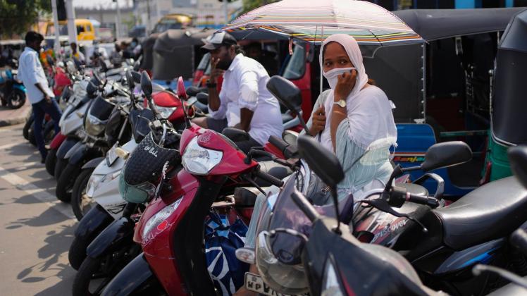 Menschen auf Motorrollern und Autorikschas warten an einer Tankstelle. Die Wirtschaftskrise in Sri Lanka hat dazu geführt, dass die 22 Millionen Einwohner des Landes mit einem Mangel an lebenswichtigen Gütern wie Medikamenten, Kraftstoff und Lebensmitteln zu kämpfen haben. Foto: Eranga Jayawardena/AP/dpa