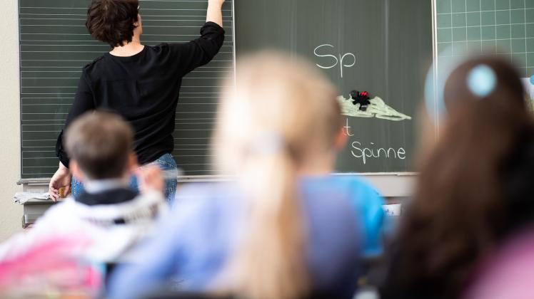 ARCHIV - Eine Lehrerin schreibt in einer Schule an die Tafel. Foto: Sebastian Gollnow/dpa/Symbolbild