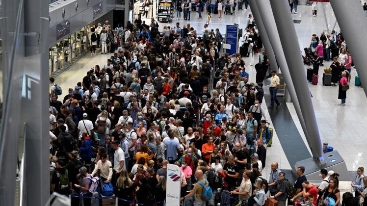 Reisende stehen während eines Warnstreiks bei der Lufthansa in Schlangen vor Check-In-Schaltern. Foto: Roberto Pfeil/dpa
