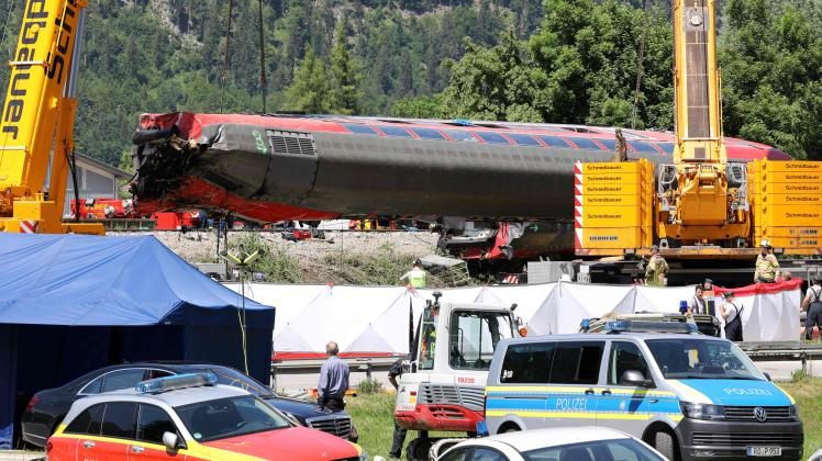 Workers use cranes to salvage a railway carriage at the site of a train derailment near Burgrain, north of Garmisch-Partenkirchen, southern Germany, on June 4, 2022, a day after the accident. - A train derailed near a Bavarian Alpine resort in southern Germany on June 3, killing at least four people and injuring dozens in a region gearing up to host the G7 summit in late June. (Photo by Dominik BARTL / AFP)