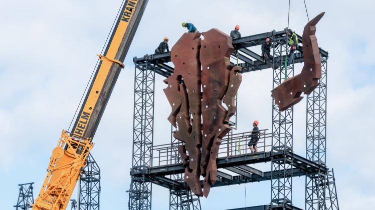 Arbeiter bauen das Wacken-Symbol auf: ein riesiger Bullenschädel. Foto: Markus Scholz/dpa