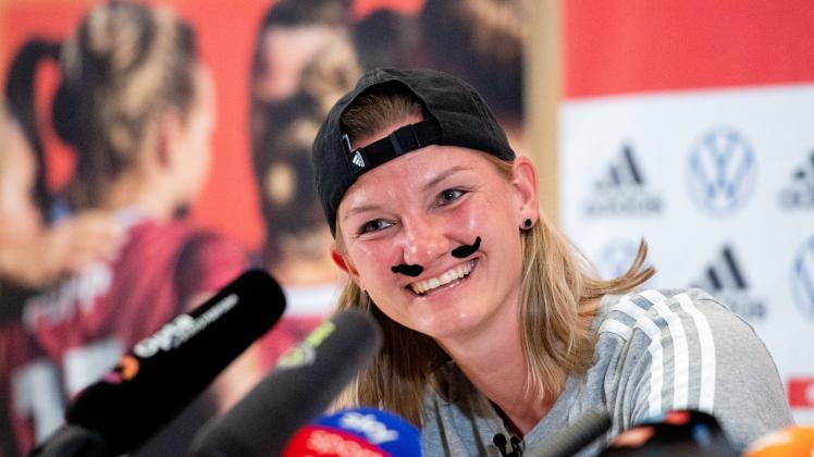Alexandra Popp (Deutschland 11) verkleidet als Alexander Bopp nach FUMMS - Meme lacht in der Pressekonferenz mit Schnau