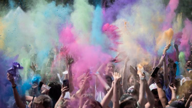Besucherinnen und Besucher tanzen zur Musik und werfen Farbpulver beim Holi Festival in Neuss. Foto: Fabian Strauch/dpa