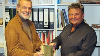 Bürgermeister Bernd Wunder (re.) übergab das alte Poesiealbum an Jürgen Bachmann, den Vorsitzenden des Chronikvereins des Kirchspiels Grundhof.