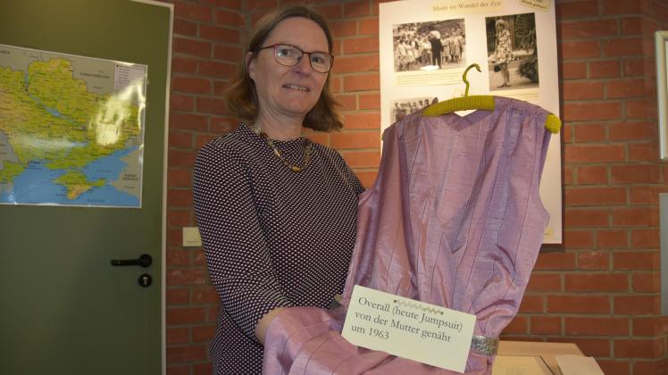Die Leiterin der Tornescher Geschichtswerkstatt Annette Schlapkohl mit einem Ausstellungsstück, das von der Mutter einer Teilnehmerin 1963 genäht wurde und heute wieder sehr in Mode ist. Damals wurde es als Overall bezeichnet, heutzutage als Jumpsuit. 