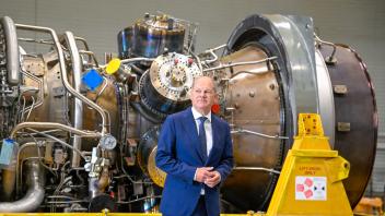 German Chancellor Olaf Scholz stands in front of a turbine of the Nord Stream 1 pipeline during a visit on August 3, 2022 at the plant of Siemens Energy in Muelheim an der Ruhr, western Germany, where the engine is stored after maintenance work in Canada. - German Chancellor Olaf Scholz on August 3, 2022 said Russia responsible for blocking the delivery of the turbine it needs to keep gas flowing to Europe. Russian energy giant Gazprom had halted operation of one of the last two operating turbines for the Nord Stream 1 pipeline due to the "technical condition of the engine" and drastically cut gas deliveries to Europe. (Photo by SASCHA SCHUERMANN / AFP)
